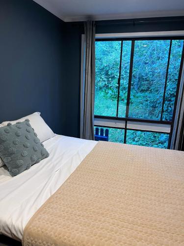 a bedroom with a bed and a large window at Morisset Cottage Blackheath in Blackheath