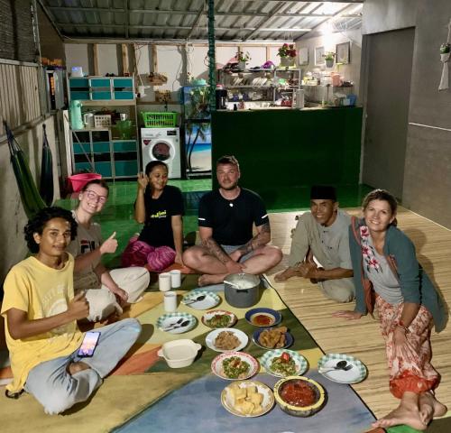 a group of people sitting around a table with food at Raturinjani homestay in Selong
