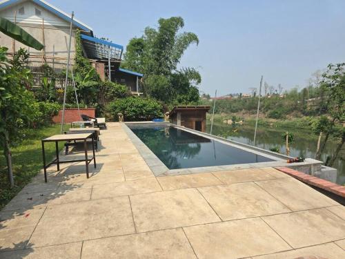 琅勃拉邦的住宿－#5 Appartement meublé + piscine.，一个带桌子和游泳池的庭院