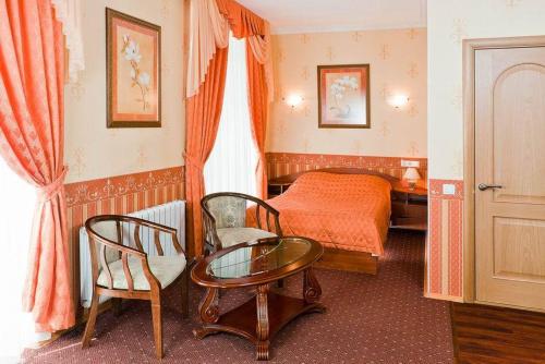 une chambre d'hôtel avec un lit, une table et des chaises dans l'établissement Galant Hotel, à Iekaterinbourg