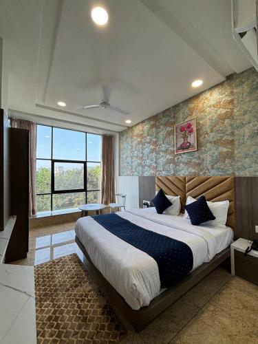 a bedroom with a large bed and a large window at Hotel Lee Pride in Anand