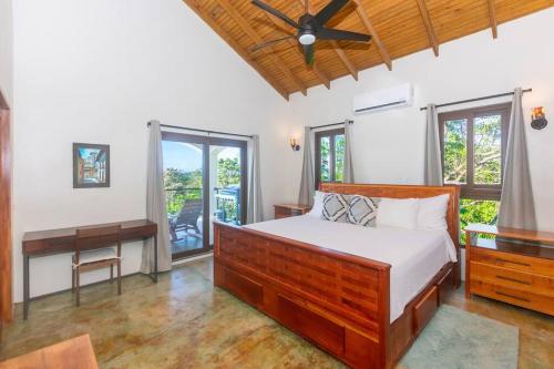 a bedroom with a bed and a desk and windows at Apricari Villa / Luxury Views / 5 BDRM / Pool in Roatan