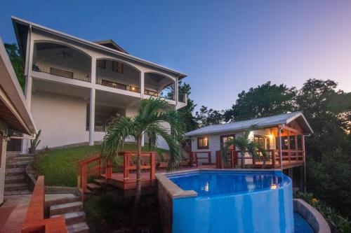 une maison avec une piscine en face de celle-ci dans l'établissement Apricari Villa / Luxury Views / 5 BDRM / Pool, à Roatán