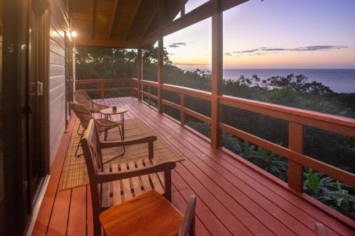 a porch with chairs and tables and a view of the ocean at Apricari Villa / Luxury Views / 5 BDRM / Pool in Roatan