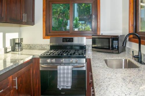 a kitchen with a stove and a microwave at Apricari Villa / Luxury Views / 5 BDRM / Pool in Roatan