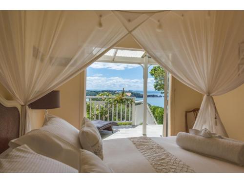 a bedroom with a bed with a view at Romantic Cottage Recommended by NZ Herald in Oneroa