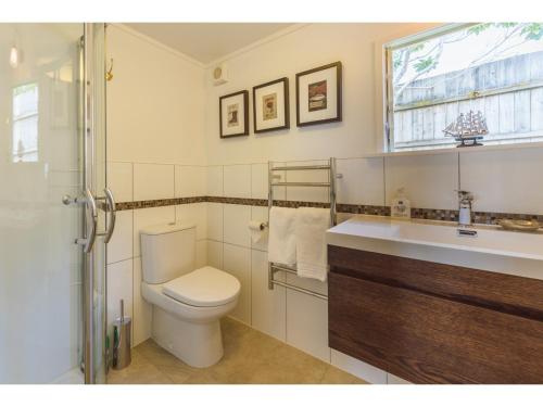 a bathroom with a toilet and a sink and a window at Romantic Cottage Recommended by NZ Herald in Oneroa