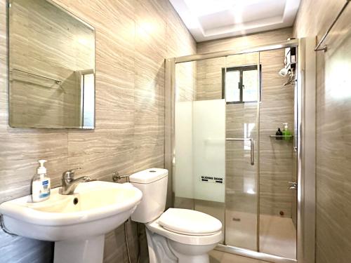 a bathroom with a toilet and a sink and a shower at Bella Homes 6BR 4Bath near Rotunda in Tagaytay
