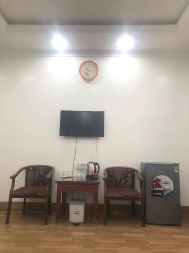 a room with two chairs and a table and a clock at Nhà nghỉ Như Ngọc in Diện Biên Phủ