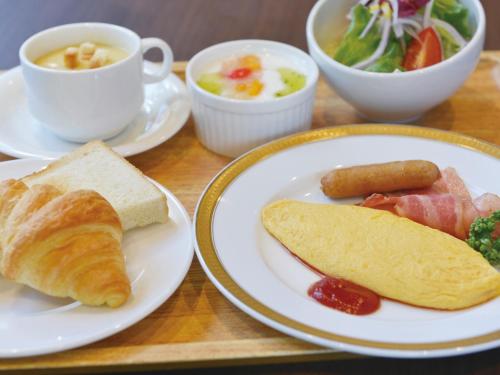 a table with plates of breakfast foods and a cup of coffee at Hotel New Gaea Omuta Garden in Ōmuta