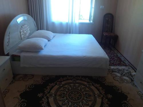 a bedroom with a white bed with a chair and a window at CBT Arkit guest house in Arkit