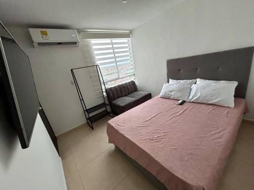een kleine slaapkamer met een bed en een stoel bij Lindo apartamento de 3 habitaciones in Cúcuta