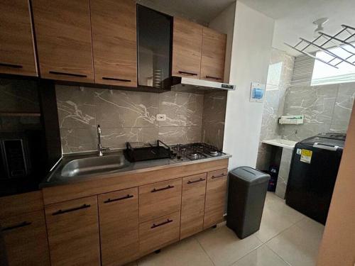 una cocina con armarios de madera y fregadero en Lindo apartamento de 3 habitaciones, en Cúcuta