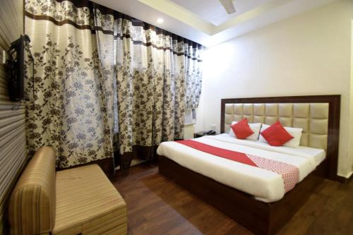a bedroom with a bed with red pillows and curtains at Super Hotel O Maa Residency in Jammu