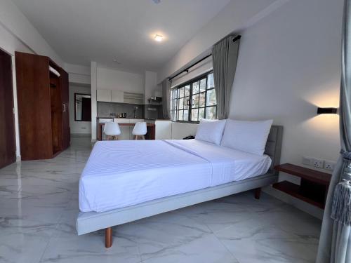 a bedroom with a large white bed and a kitchen at 88th Nuwara Eliya in Nuwara Eliya