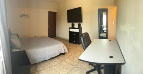 Dormitorio con cama, escritorio y TV en Habitación Roble, en Saltillo