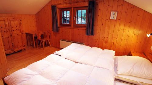 a large bed in a room with wooden walls at Chalet Heimeli in Saas-Fee