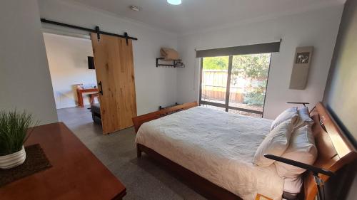 1 dormitorio con 1 cama y puerta corredera de cristal en Red Ochre – Large 1BR with Private Courtyard, en Port Pirie