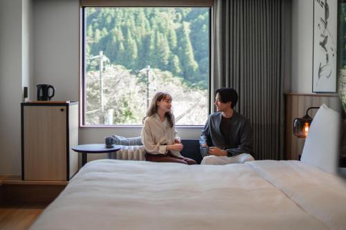 a man and a woman sitting next to a bed at Fairfield by Marriott Gifu Gujo in Gujo