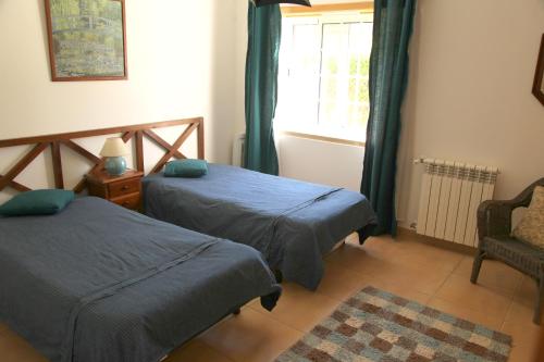 a bedroom with two beds and a chair and a window at Villa Casa Dina in Casal da Lagoa Seca