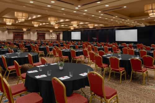 a conference room with round tables and red chairs at Des Moines Marriott Downtown in Des Moines