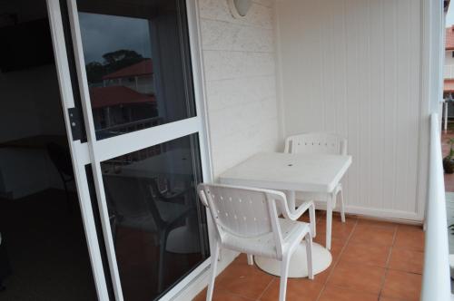 - Balcón con mesa blanca y sillas en Monte Carlo Motor Inn, en Townsville