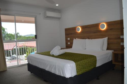 a bedroom with a large bed and a balcony at Monte Carlo Motor Inn in Townsville