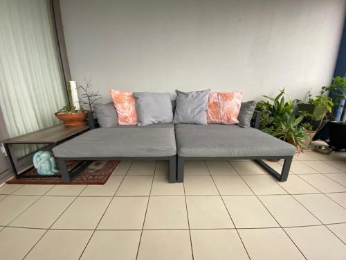 a gray couch with pillows on top of a room at It's Paradise Here, Private Room with Breakfast and 2 cats in Wollongong