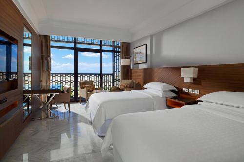 um quarto de hotel com duas camas e uma mesa e cadeiras em Sheraton Tunis Hotel em Tunes