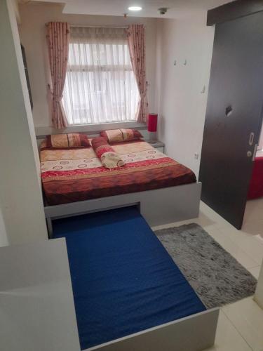 una piccola camera con letto e pavimento blu di Apartement Grand Asia Afrika Residence Bandung a Bandung