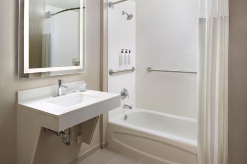 a white bathroom with a sink and a bath tub at SpringHill Suites Raleigh-Durham Airport/Research Triangle Park in Durham