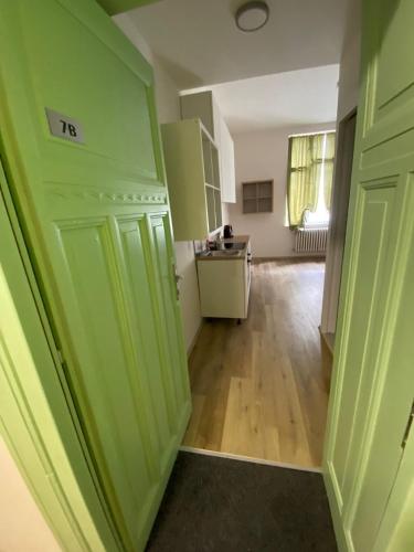 an empty room with green doors and a kitchen at MINATO Apartments Ostrava center in Ostrava