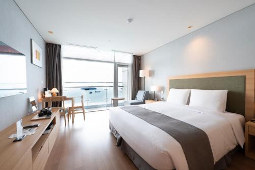 a hotel room with a large bed and a desk at Hidden Bay Hotel in Yeosu