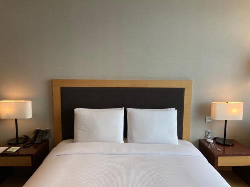 a bedroom with a large bed with white sheets and two lamps at Hidden Bay Hotel in Yeosu