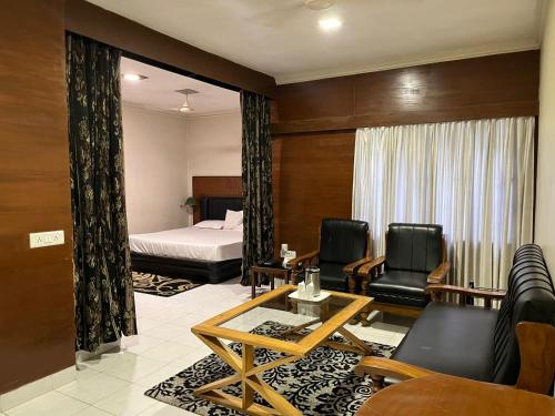 a hotel room with a bed and two chairs at Hotel The Galaxy in Mirzāpur