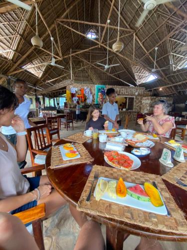 a group of people sitting around a table eating food at Kiwengwa Bungalow Boutique Resort in Kiwengwa