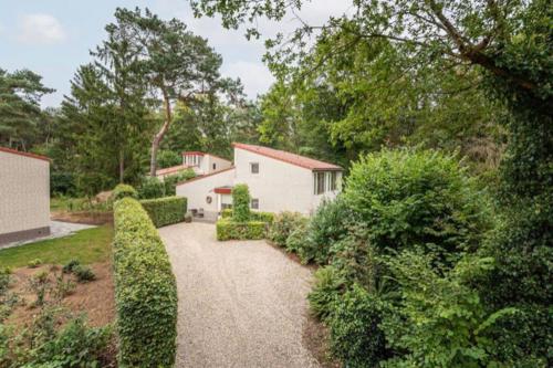 a driveway leading to a house with bushes and trees at Vakantiehuis midden in de natuur in Halle