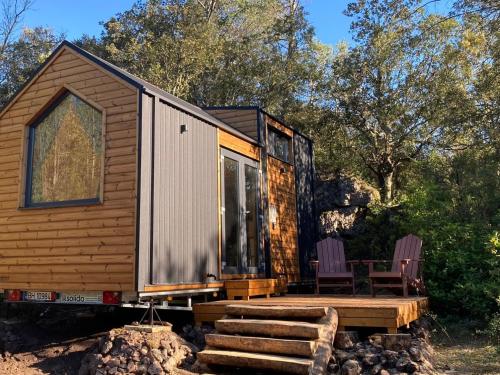 a tiny house with two chairs and a porch at Roque Rouge Cottage by Tiny Away in Bédarieux