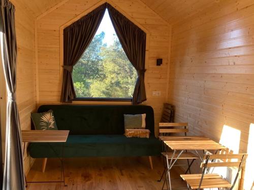 - un canapé vert dans une chambre avec une grande fenêtre dans l'établissement Roque Rouge Cottage by Tiny Away, à Bédarieux