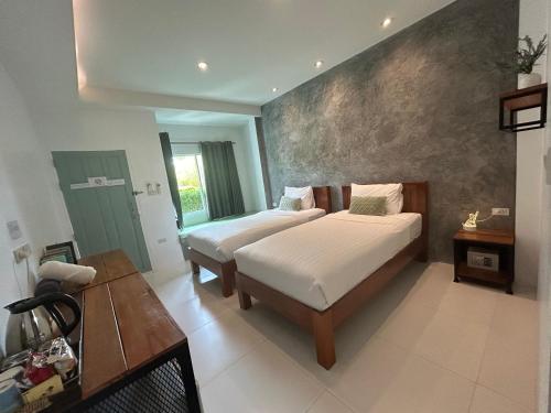 1 dormitorio con 2 camas y mesa. en Phangan Hometown Resort - Adults Only, en Baan Tai