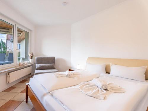 a bedroom with a large white bed and a chair at Air Comfortable holiday residence in Ostseebad Koserow