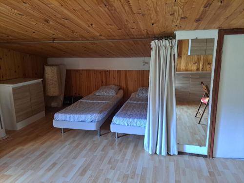 two beds in a room with wooden walls and wood floors at Joli appartement in Valdeblore