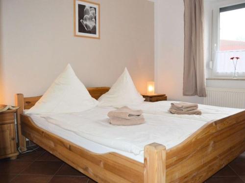1 dormitorio con cama de madera con sábanas blancas y ventana en Windrose Comfortable holiday residence en Norddeich