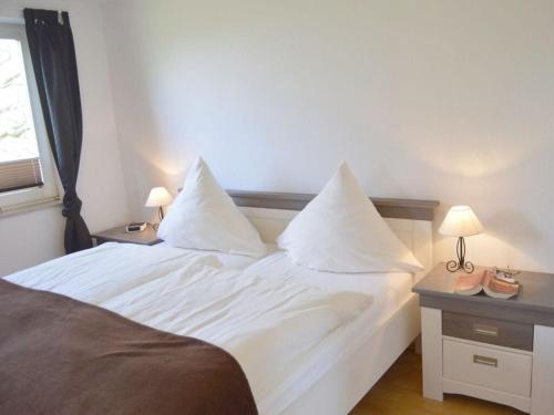 Schlafzimmer mit einem Bett mit weißer Bettwäsche und Kissen in der Unterkunft Deichstübchen Comfortable holiday residence in Norddeich