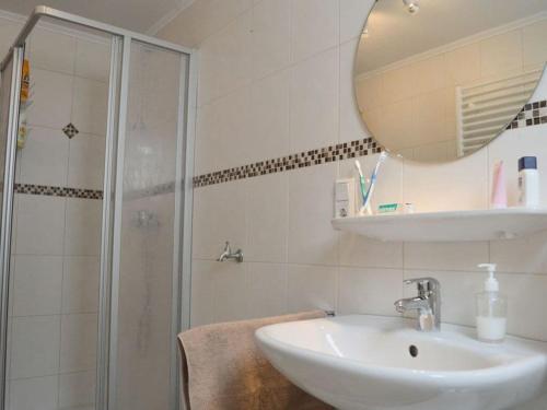 uma casa de banho com um lavatório e um chuveiro com um espelho. em Deichstübchen Comfortable holiday residence em Norddeich