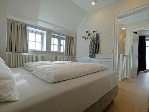 a large white bed in a bedroom with windows at By the sea Comfortable holiday residence in Dranske