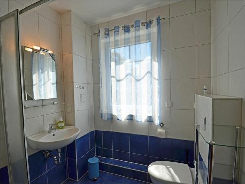 a bathroom with a sink and a toilet and a window at Albatros Comfortable holiday residence in Juliusruh