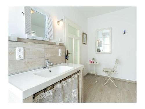 a white bathroom with a sink and a chair at Three-master house no 1 in Breege