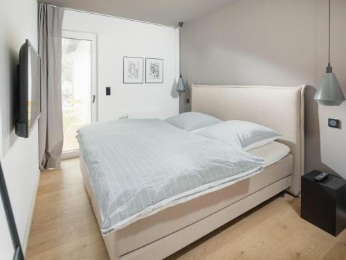 a white bedroom with a bed and a window at Mooi 3 Comfortable holiday residence in Norderney