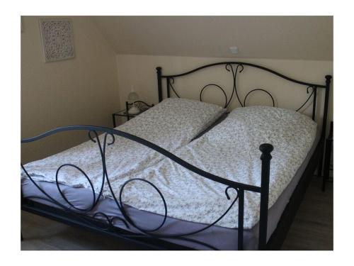 a bed with a black frame and a white comforter at Scheel Comfortable holiday residence in Nordstrand